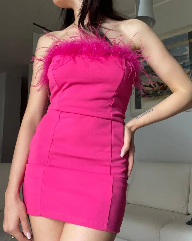 Abito a tubino fucsia con piume senza spalline.