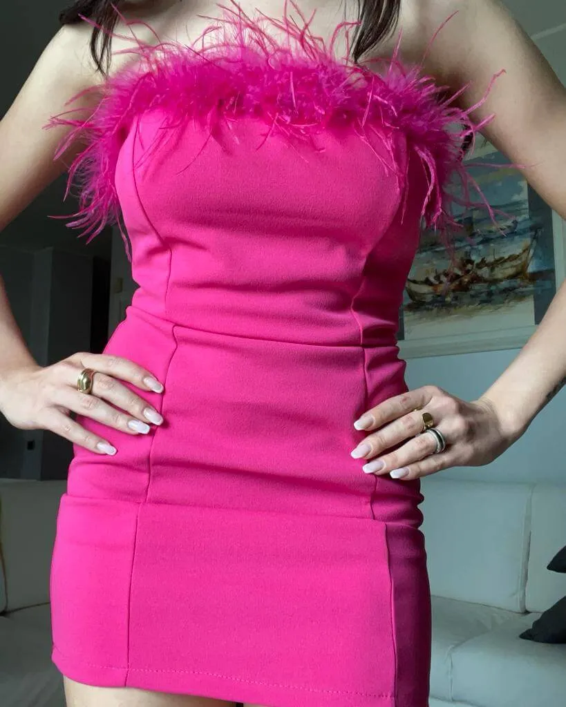 Abito a tubino fucsia con piume senza spalline.